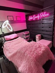 a pink bed sitting in a bedroom next to a neon sign