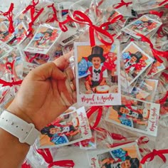 a person holding up some small cards with red ribbon around the edges and an image of mickey mouse on them