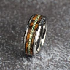 a wedding ring with an orange and green pattern on the inside is sitting on a gray surface