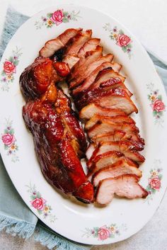 sliced pork on a plate with sauce and flowered napkins next to the meat