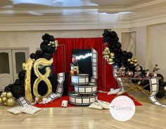 a birthday party with black and gold decorations, balloons and streamers on the floor