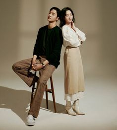 a man and woman sitting on a chair posing for a magazine cover photo with their arms around each other