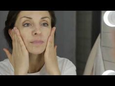 a woman with her hands on her face looking at the camera in front of a mirror