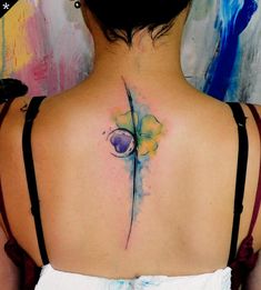 the back of a woman's neck with a watercolor tattoo design on it