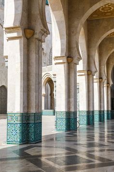 the inside of an ornate building with blue and white tiles on the floor, pillars and arches