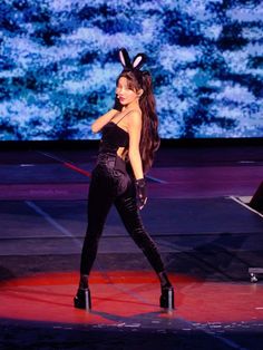 a woman in bunny ears is on stage with her hands behind her back as she walks