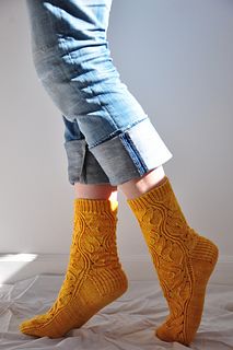 the legs of a person wearing yellow socks and blue jeans, standing on a bed