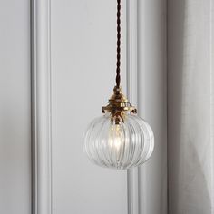 a light fixture hanging from the ceiling in front of a white wall with a brown cord