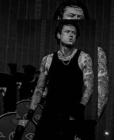 a black and white photo of a man with tattoos on his arm holding a microphone