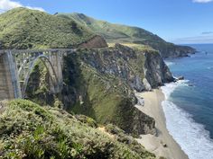 a bridge over the ocean with mountains in the background