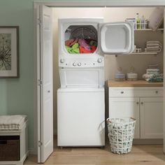 a white washer sitting inside of a kitchen next to a laundry basket and microwave