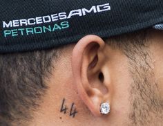 a close up of a person wearing a hat with tattoos on their ears and behind his ear