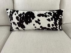 a black and white cow print pillow sitting on top of a couch