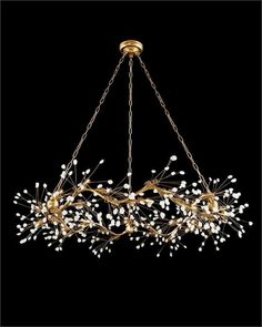 a large chandelier with white flowers hanging from it's golden chain on a black background