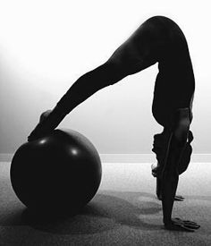 a woman doing yoga on an exercise ball in the middle of a room with her legs bent up