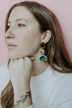 a woman with tattoos on her arm wearing earrings