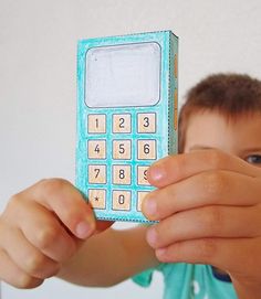 a young boy holding up a toy cell phone with numbers on the front and sides