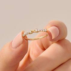 a woman's hand holding a gold ring with diamonds