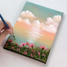 a person is holding a pencil and painting flowers