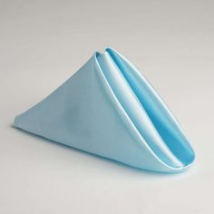 a blue folded napkin sitting on top of a white table