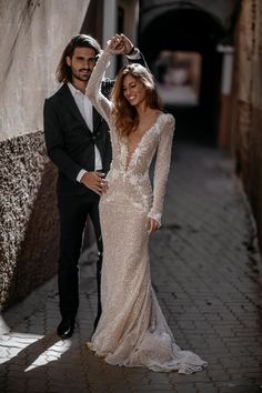 a man and woman in formal wear standing next to each other on a brick walkway