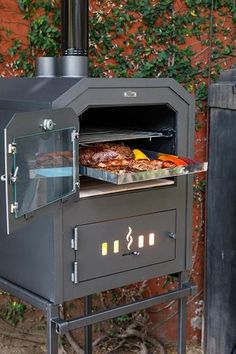 an outdoor oven with food cooking in it on top of a table next to a brick wall