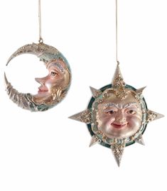 two ornaments with faces hanging from chains on white background, one has a crescent moon and the other has a smiling man's face