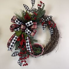 a christmas wreath with red berries and greenery on the front, hanging from a wall