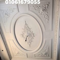 the ceiling is painted white and has ornate designs on it, as well as a clock