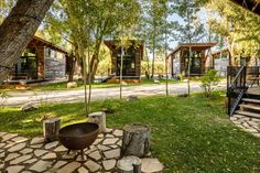 an outdoor area with trees, benches and fire pit in front of the cabin buildings