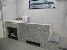 a bathroom with tiled walls and flooring next to a sink in front of a window