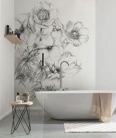 a white bath tub sitting next to a wall with flowers painted on the side of it