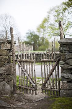 an old wooden gate that has been made into a rock wall and is surrounded by grass