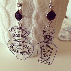 the earrings are decorated with an image of a perfume bottle