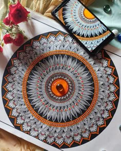 an orange and black plate sitting on top of a table next to a cell phone