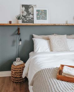 a bed with white linens and pillows in a bedroom next to a wooden shelf