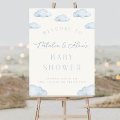 a welcome sign for a baby shower is displayed on an easel in front of some lights