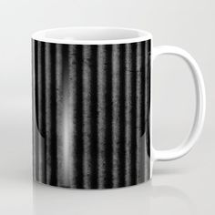 a black and white coffee mug with vertical stripes on the side, in front of a plain background