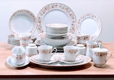 a table topped with lots of white plates and cups on top of a wooden table