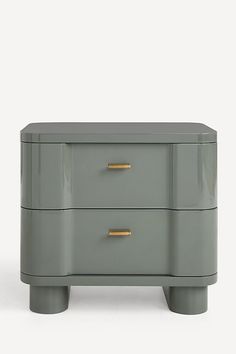 a grey dresser with two drawers and gold handles on the top, against a white background