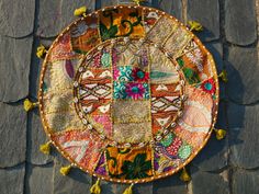 a decorative plate with tassels on it sitting on top of a stone wall