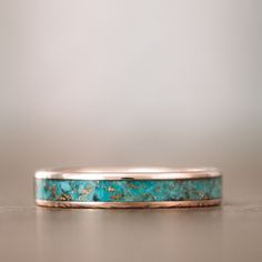 a turquoise stone ring sitting on top of a table