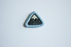 a blue and white patch with a mountain in the middle on it's side