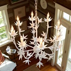 a white chandelier hanging from the ceiling in a room with wood floors and windows