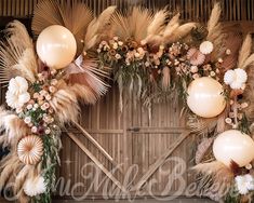 an arrangement of flowers, feathers and balloons for a rustic wedding arch with the word love written on it