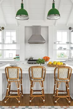 two green lamps are hanging over the kitchen island in this white and wood - paneled kitchen