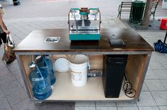 a coffee machine sitting on top of a wooden table next to two blue water containers