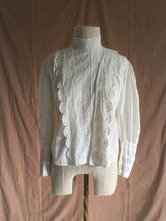 "vintage early 1900s antique true vintage blouse white cotton embroidered cotton lace mother of pearl buttons (except bottom button which is something else, maybe plastic) eyelet detail lace trim right of center buttons up front hidden under lace flap the button placement makes this seem to be originally meant for breast feeding  tie back hook eye back neck mutton chop sleeves front hem is longer than back hem good vintage condition  considering age w/signs of wear mended holes, fray, light tea/rust color stains here and there the buttons had wear around them enough for me to put patches under the buttons for re-enforcement all the buttons don't match but are of the era patches around back tie area patches around neck area repairs by me wearable measures, lying flat, shoulder-15 1/2\" ches Victorian Cotton Fitted Blouse, Fitted Victorian Cotton Blouse, Victorian Cotton Blouse With Lace Collar, Vintage Fitted Tops With Broderie Anglaise, Victorian Long Sleeve Cotton Blouse, Wedding Blouse With Lace Trim In Cotton, Vintage Long Sleeve Blouse With Broderie Anglaise, Vintage Long Sleeve Broderie Anglaise Blouse, Vintage Lace Blouse With Broderie Anglaise