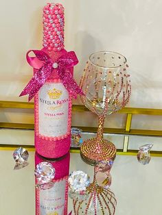 a bottle of pink wine sitting on top of a table next to a crystal goblet