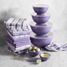 purple dishes stacked on top of each other with bowls and spoons next to them